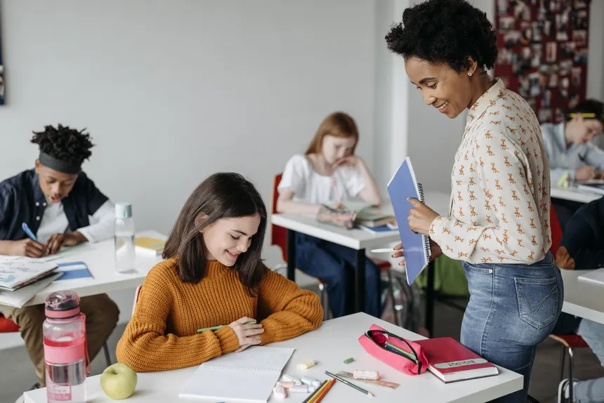 Teacher assisting students in a classroom setting, fostering a learning environment.