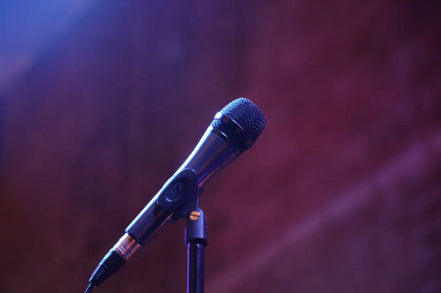 A microphone on a stand against a blurred background, perfect for music or event themes.
