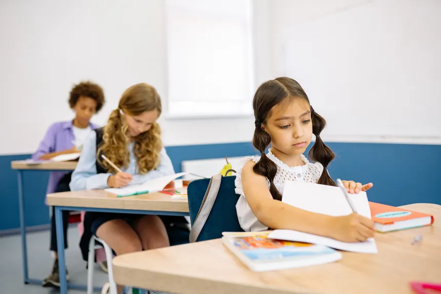 Young students focusing on their studies at desks inside a classroom.