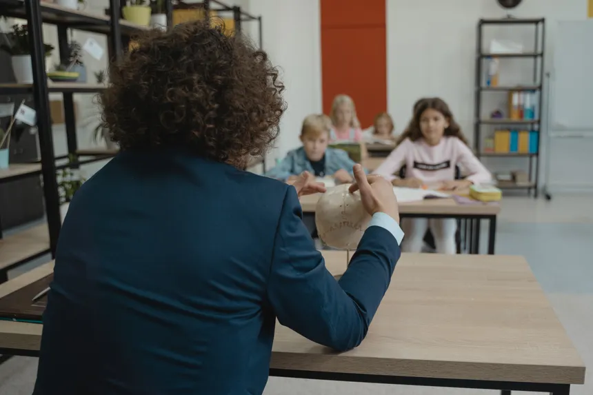 A teacher explains anatomy using a skull model in a classroom setting with students.