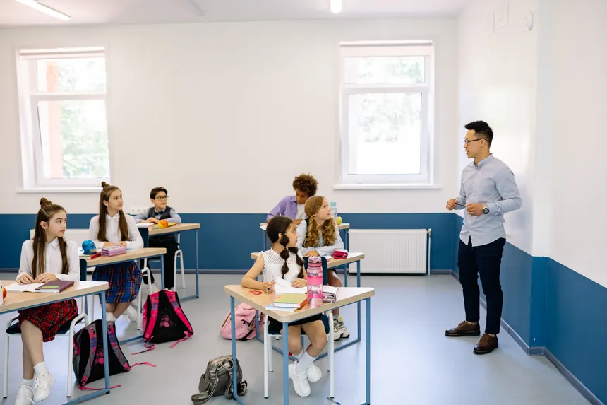 Students attentively listening to a teacher during a classroom lesson.