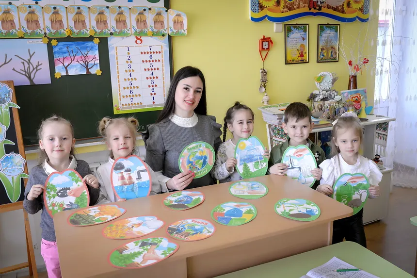 Children and teacher engaging in a classroom activity with art projects.