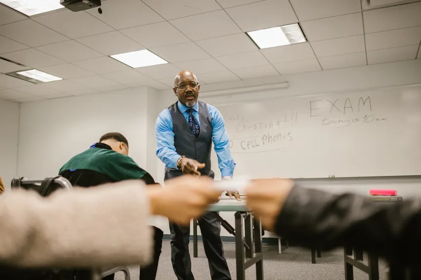 Students interacting with a teacher in a classroom during an exam, focusing on academic integrity.